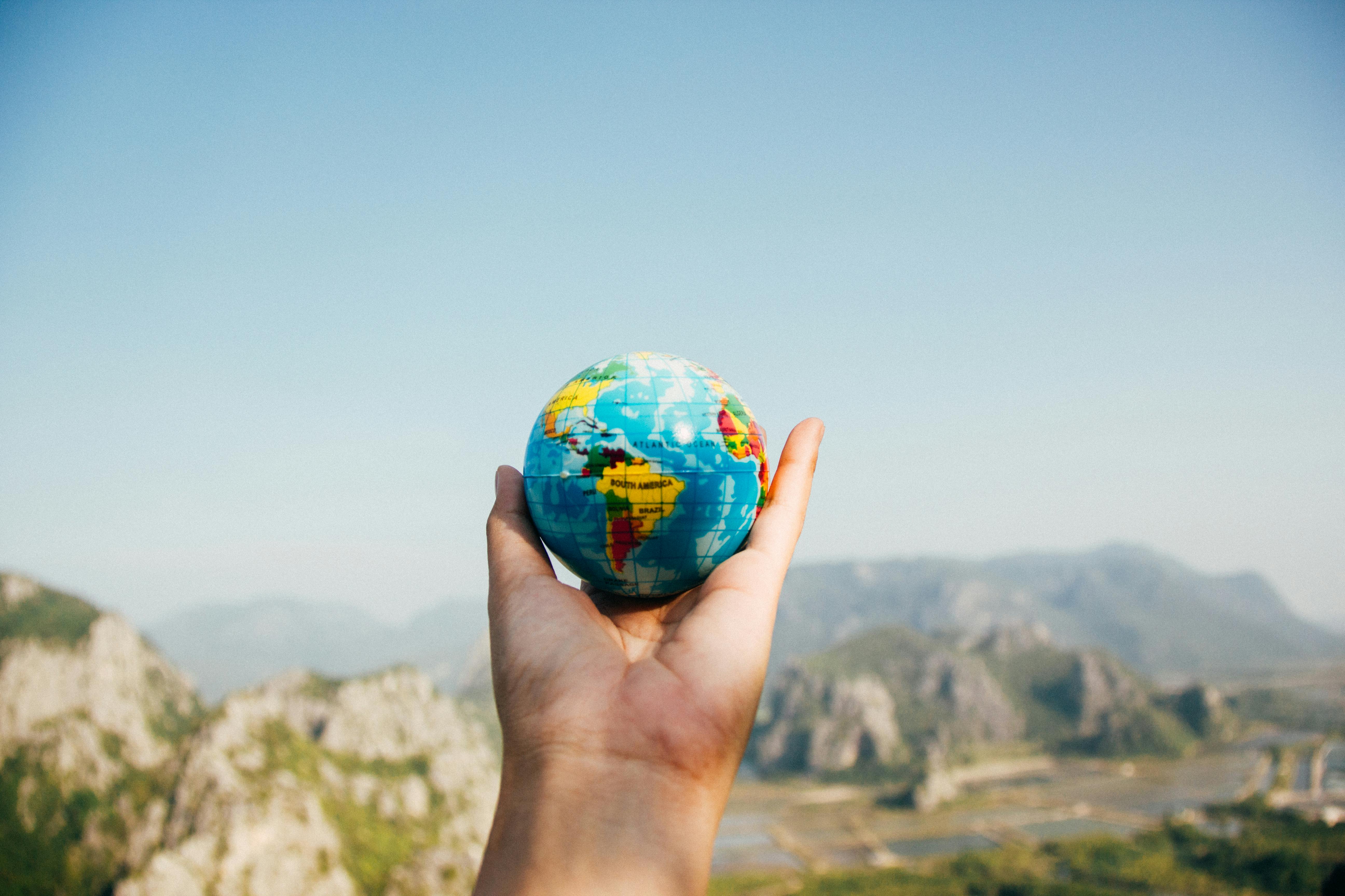 A person holding a tinny globe